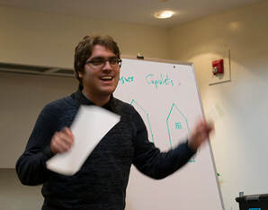 Image of Alex Benarzi holding a script in one hand, teaching Shakespeare.
