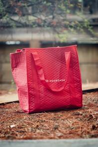 Picture: a red DoorDash bag sitting on the grass.